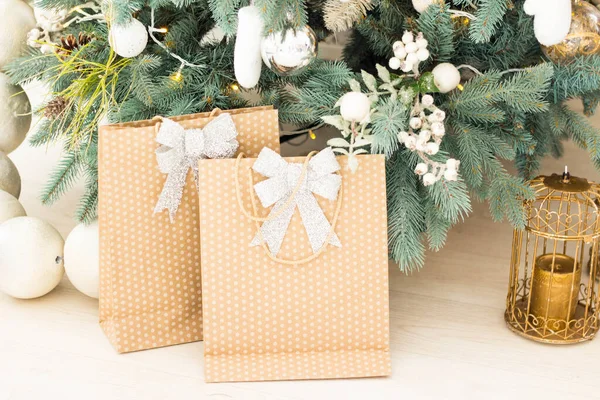 Stijlvolle kerstcadeau dozen op houten vloer onder kerstboom. Cadeaus en ornamenten in en papieren zakken. Vakantie winkelen. Geschenkverpakkingen — Stockfoto