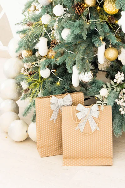 Stijlvolle kerstcadeau dozen op houten vloer onder kerstboom. Cadeaus en ornamenten in en papieren zakken. Vakantie winkelen. Geschenkverpakkingen — Stockfoto