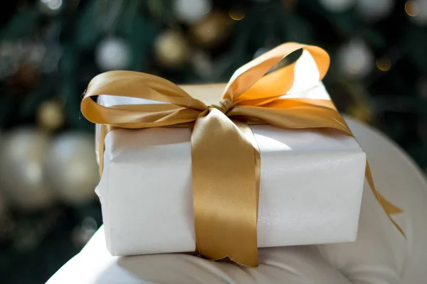 Opklaren. Kerst gouden geschenken liggen onder de kerstboom. Grote geschenkdozen zijn wit met gouden lint. — Stockfoto