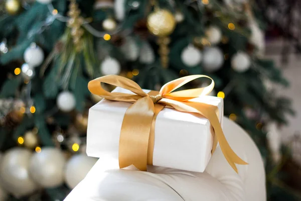 Nieuwjaarsgeschenken liggen onder de kerstboom. Grote geschenkdozen zijn wit met gouden lint op de vloer. — Stockfoto