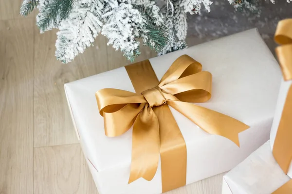 Opklaren. Kerst gouden geschenken liggen onder de kerstboom. Grote geschenkdozen zijn wit met gouden lint. — Stockfoto