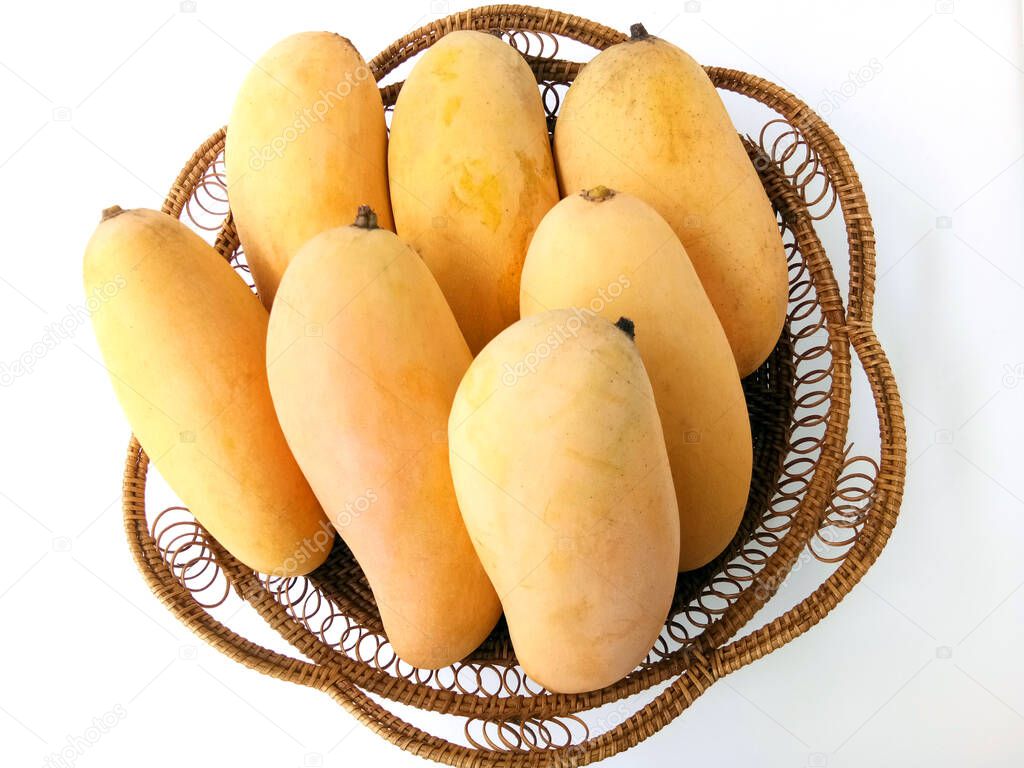 Yellow ripe mangoes in a basket on white background.