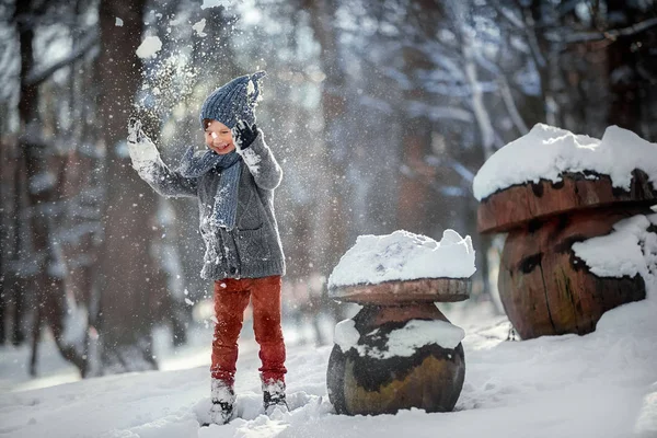 一个穿着毛衣 手套的小男孩在冬天的公园里扔雪 闭着眼睛笑着 — 图库照片