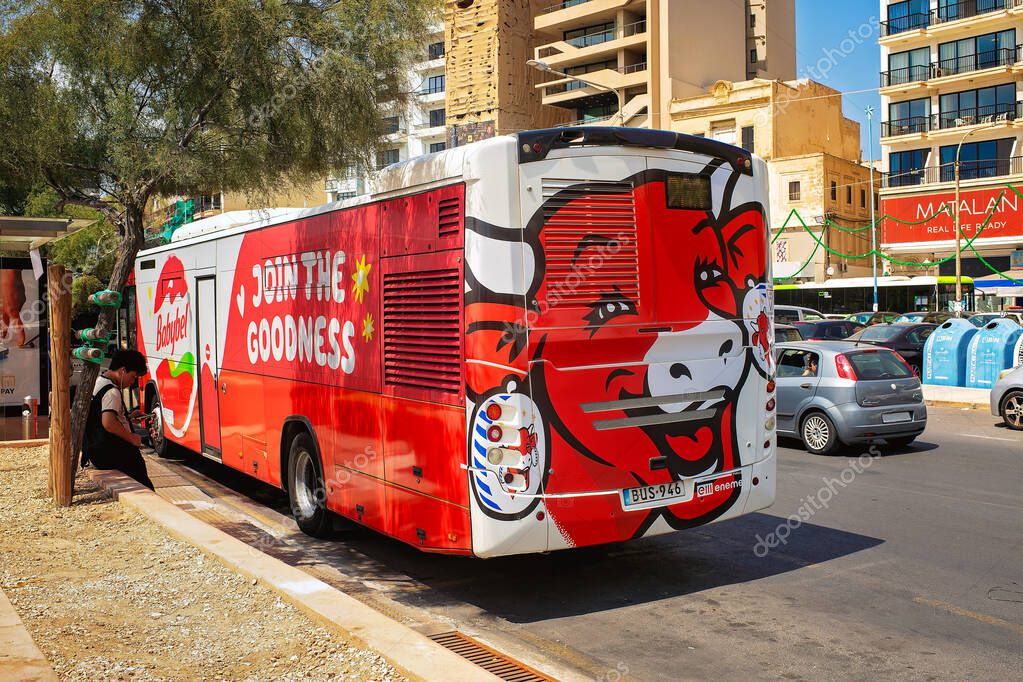 Sliema, Malta - August 26, 2025: City bus with babybel advertising and cow illustration parked on street among buildings and cars