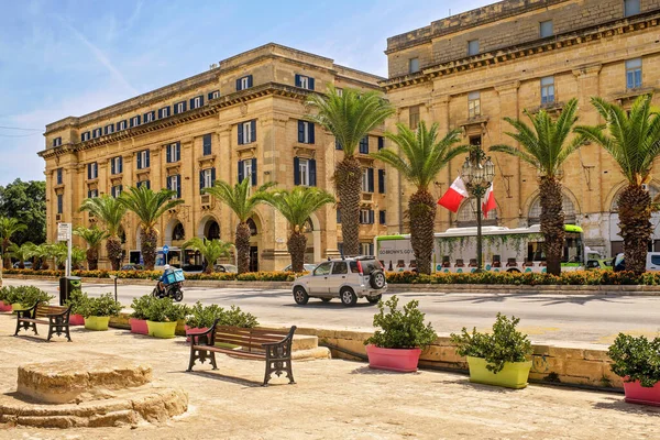 Floriana, Malta - 09.03.2025: Tarihi mimarisi, palmiye bulvarı, trafiği yoğun yolu ve bankları ve saksı bitkileri olan bir meydan.