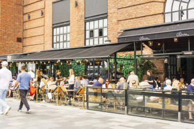 Oslo, Norveç - 22 Haziran 2025: İnsanlar Norveç 'in Oslo kentinde Harbour Promenade' deki bir restoranda güneşli havanın tadını çıkarıyor ve yemek yiyor.