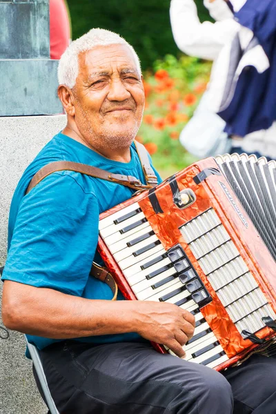 Oslo, Norveç - 22 Haziran 2025: Oslo 'da bir taburede oturmuş akordeon çalan yaşlı bir sokak müzisyeninin portresi