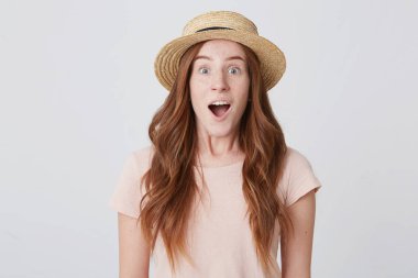 Açık ağız ile ayakta ve beyaz arka plan üzerinde hayran duygu hasır şapka sürpriz heyecanlı Kızıl saçlı Sevimli genç kadında