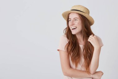 Neşeli güzel kızıl saçlı Genç kadın uzun saçlı ve çilli bir yan seyir beyaz arka plan üzerinde gülüyor hasır şapkalı closeup