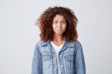 Mutsuz ve üzgün üzgün güzel genç kadın Uzun Kıvırcık Kızıl saçlı kot ceket giyer ve beyaz arka plan üzerinde onun dudak ısırma stres hissediyor