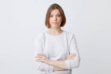 Mutsuz memnun genç kadın longsleeve ayakta elle katlanmış ve beyaz arka plan üzerinde izole hayal kırıklığına hissediyor