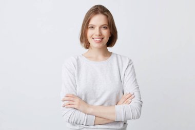 Gülümseyen güzel genç kadın longsleeve ayakta silah ile geçti ve duygu kendinden emin beyaz arka plan üzerinde izole başarılı görünüyor