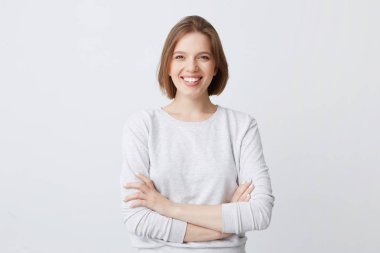 Longsleeve ayakta silah ile neşeli çekici genç kadın portresi geçti ve beyaz arka plan üzerinde izole gülümseyerek emin görünüyor