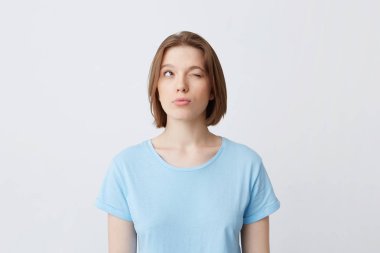 Düşünceli konsantre genç kadın mavi t gömlek düşünme ve sınavı soru cevapları hatırlamaya çalışarak beyaz bitti izole bir kapalı gözlerle duvar Looking yana ve yukarı