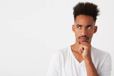 Closeup of thoughtful attractive african american young man with curly hair wears t shirt looks pensive and thinking isolated over white background Looks to the side clipart