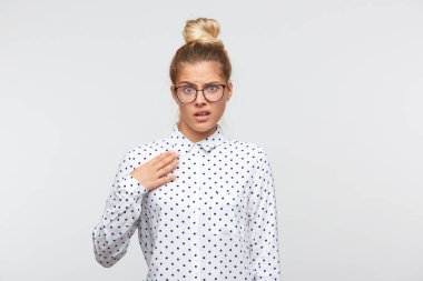 Topuz ile mutsuz genç kadın closeup puantiyeli gömlek giyer ve gözlük memnun hissediyor ve kendini beyaz arka plan üzerinde izole, puan