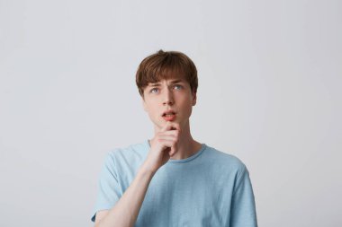 Mavi t-shirt, Genç adam portresi kol çeneme tutar ve örnek alıyor, fikri düşünen, farklı varyantları, beyaz arka plan üzerinde sorunlu, sorunu çözmek için ne düşünüyorum düşünün