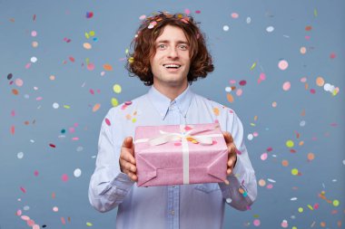 A man came for a holiday, giving a gift, in his hands a pink box tied with a white ribbon, smiling and ready to say many warm words to a birthday man. clipart