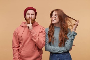 Oynak gülümseyen genç zencefil erkek, Kapalı atış görünüyor bir yana onu boyfried. Erkek kızgın ve öfkeli ve sessizlik jest gösterir. Biege'e arka plan üzerinde izole