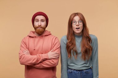 Kapalı atış zencefil genç kadın uzun saçlı, casualy giyer, gülümsüyor. Onun yanında duran arkadaşı. Adam katlanmış el tutar, kaş yükseltmek ve yüz ifadesi hayret.