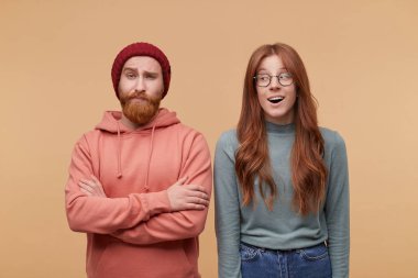 Uzun saçlı Genç zencefil kadın kapalı atış casualy giyer, gülümsüyor ve onun arkadaşı onun yanında duran bir yana görünüyor. Adam katlanmış el tutar, kaş yükseltmek ve yüz ifadesi hayret.