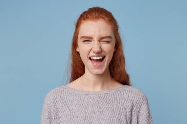 Neşeli neşeli Kızıl saçlı kız, fotoğraf makinesi, göz kırpıyor şakacı görünüyor, kadınlar, eğleniyor, izole mavi bir arka plan üzerinde pozitif bir ruh hali ile kurmuştur.