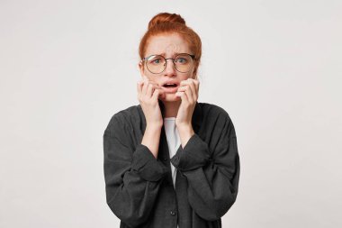 Şok korkmuş zencefil kız portresi görünüyor mavi arka plan üzerinde kafa, holding korkmuş korkuyor, eller