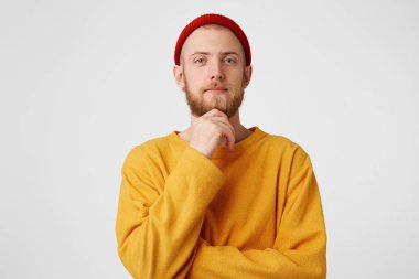 Düşünceli adam beyaz arka plan duvardan izole fotoğraf. Düşünme kibirli kendine güvenen genç sakallı erkek holding yumruk çene üzerinde