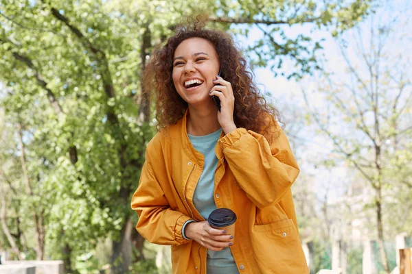 Gelukkig lachen krullend darck skined meisje, het dragen van een gele jas, — Stockfoto