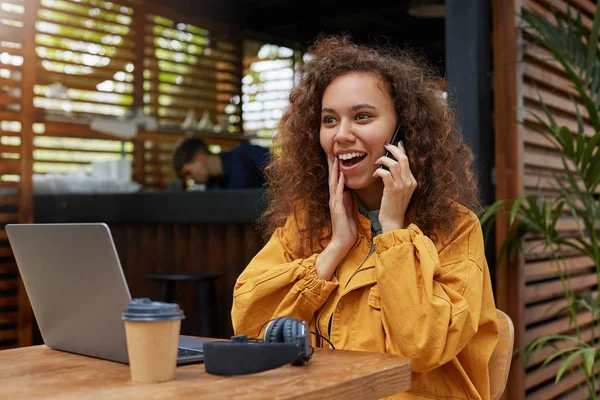 Handsome young dark skinned curly woman siting on a cafe terrace