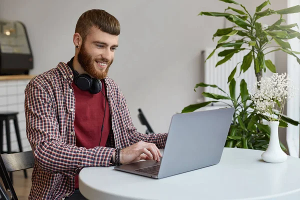 Gelukkig jonge aantrekkelijke gember bebaarde man werken op een laptop WH — Stockfoto