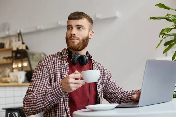앉아있는 동안 노트북에서 일하는 매력적인 생강 수염 남자 — 스톡 사진