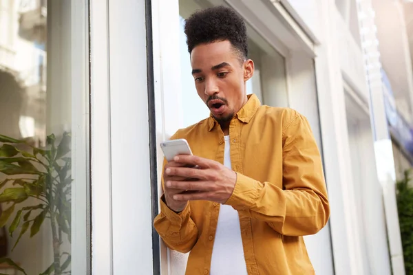 Photo de jeune homme à la peau foncée étonné en chemise jaune marchant d — Photo