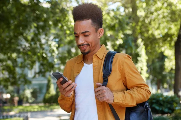 Jeune homme afro-américain insatisfait en chemise jaune, chattin — Photo