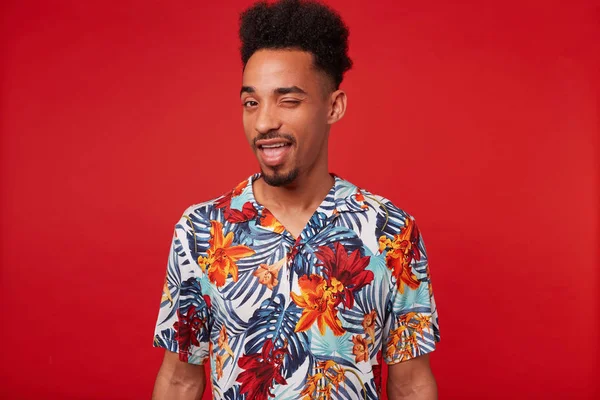 Young positive African American man wears in Hawaiian shirt, loo