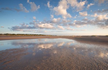 Kumlu ortamda su, suda bulut yansımaları.