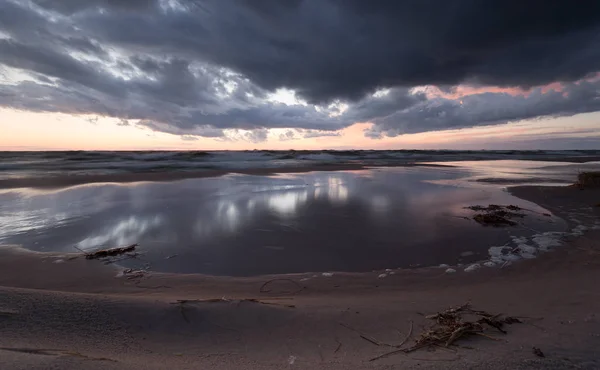 Sunset over the ocean with the clouds reflecting in the water