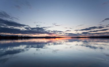 Sakin bir İsveç gölünün üzerinde gün batımı