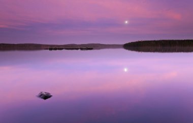İsveç 'in ortasında sakin bir gölün üzerinde güzel bir gün batımı.