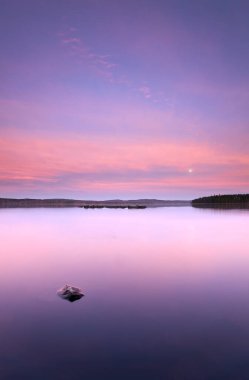 Sakin bir İsveç gölünün üzerinde gün batımı