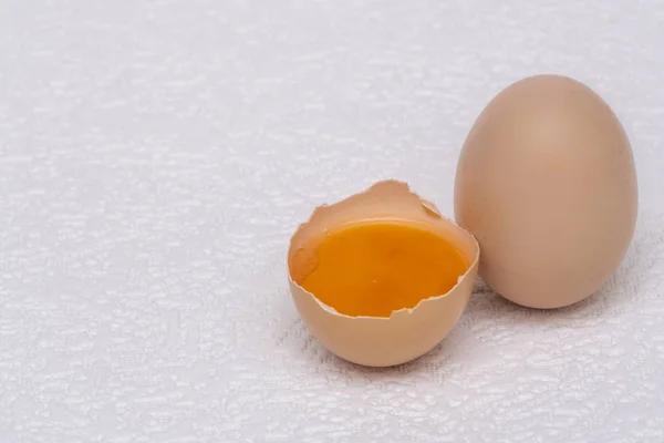 Broken and whole brown eggs on a white surface — Stock Photo, Image