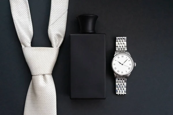 Set of men\'s accessories, watches, necktie, perfumes on a dark background.