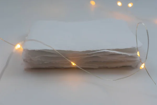 A stack of handmade paper in a festive decoration with lights. The concept of gifts for Christmas and New Year.