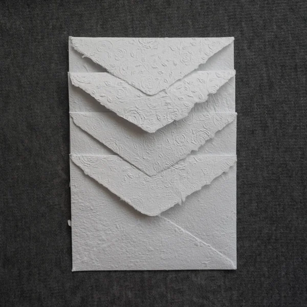 Handmade paper mail envelopes lie in a row on a gray surface. Paper recycling and zero waste concept.