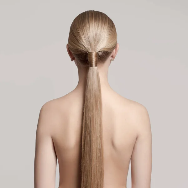 woman with a hair tail. Back view. Gray background.