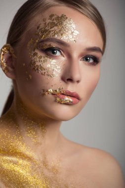 Kadının yüzü yakın çekim. Yüzünde altın