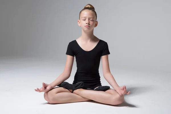 Uma jovem está sentada numa pose de lótus. Meditação. Criança. Yoga infantil. Desporto infantil. Ginástica infantil Imagens Royalty-Free