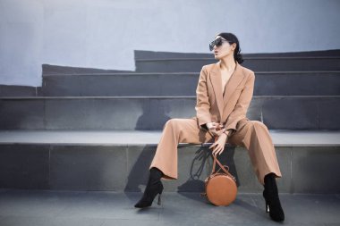 Merdivenlerde oturan başarılı bir iş kadını moda portresi. Şehir arka planı