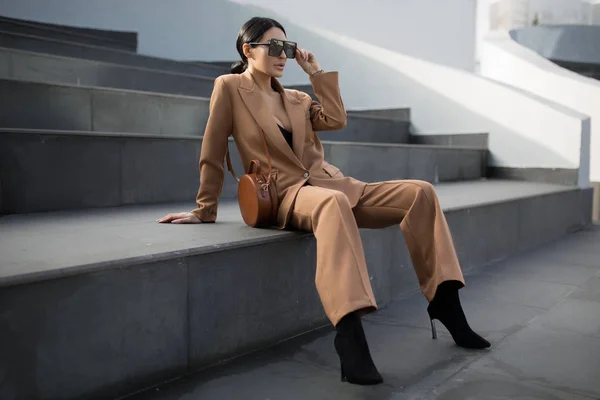 Merdivenlerde oturan başarılı bir iş kadınının portresi. Telefon onun ellerinde. Şehir arka planı