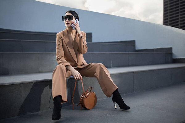 Portrait of a successful business woman sitting on stairs. the phone is in her hands.